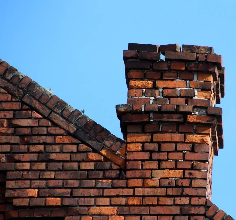 Damaged chimney on an Utica home showing cracks and missing mortar